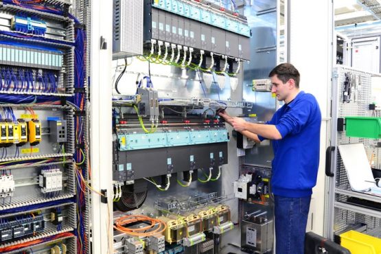 Facharbeiter montiert elektronische Schaltanlage in einer Fabrik // workers mounted switchgear in an industrial plant